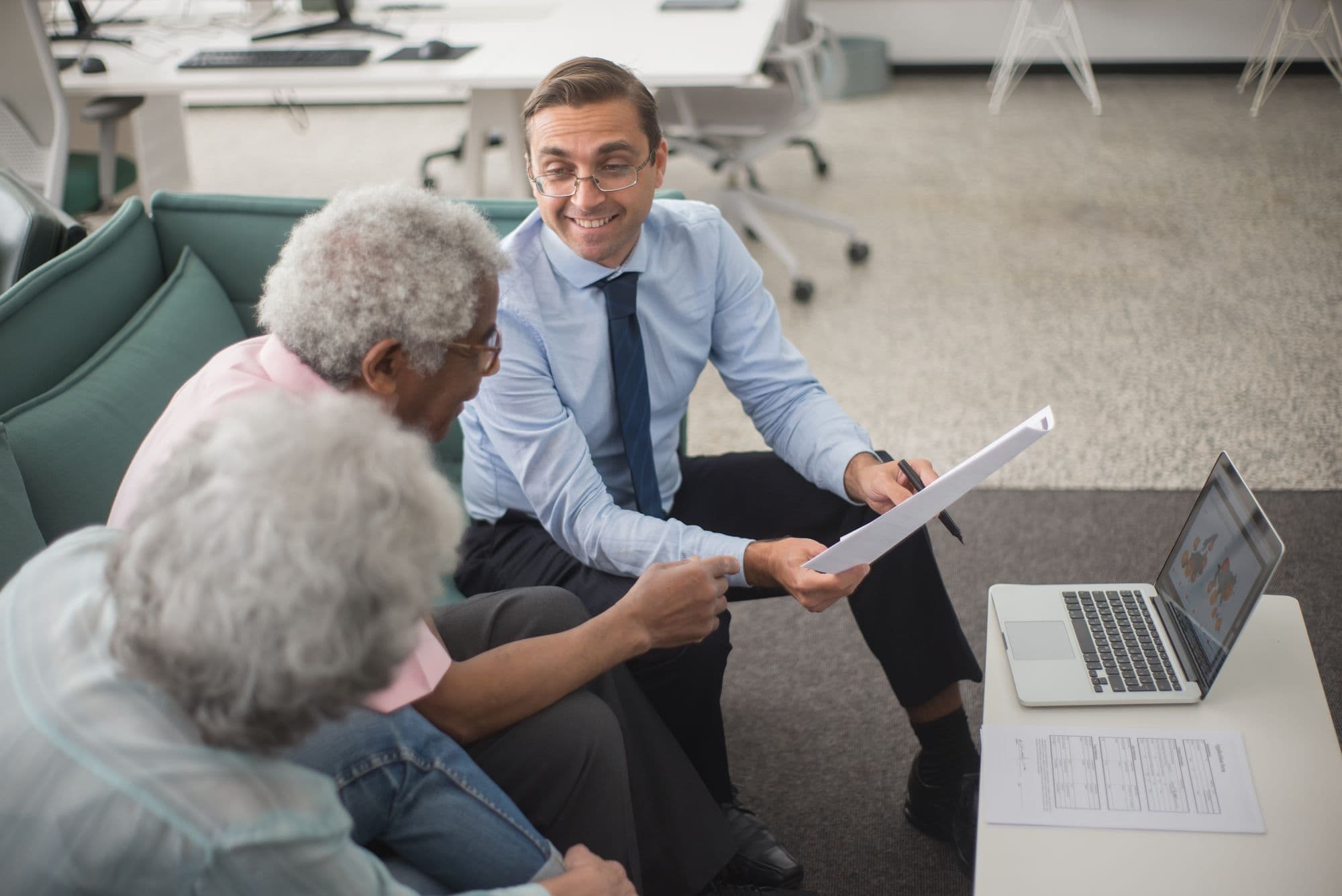 An advisor reviewing financial planning documents with two seated clients in an office